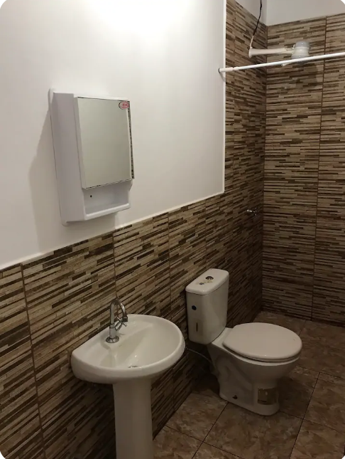 A white sink sitting next to a brick wall

Description automatically generated